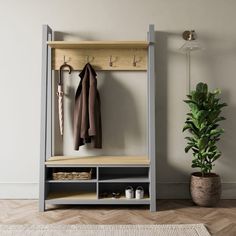 a coat rack with two coats hanging on it and a potted plant next to it