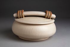 a white pot with two wooden handles on it's sides and a brown cord sticking out of the top