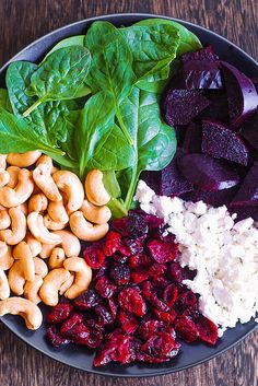 a plate filled with vegetables and nuts on top of a wooden table