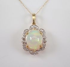 "Yellow Gold Diamond and Opal Pendant Necklace. The Necklace is set with one Oval Opal Cabochon in the center.  This Opal measures 11 X 9 mm and weighs 2 carats.  There are thirty Round Brilliant Diamonds set in this pendant. These diamonds are H color, SI/I1 clarity and weigh a total of .18 carat.  The pendant is 10K Yellow Gold and comes with an 18\" 10K Yellow Gold chain and together weigh 2.3 grams.  The pendant measures 17 X 14 mm without the bail.  This necklace will be accompanied by an a Diamond Cabochon Necklace For Anniversary, Diamond Cabochon Pendant Necklace, Classic White Jewelry With Gemstone Accents, Elegant Oval Stone Setting Necklaces, White Cabochon Fine Jewelry Necklace, White Necklace With Stone Setting For Formal Occasions, Formal White Necklace With Stone Setting, Oval Stone Setting Necklaces For Anniversary, Oval Stone Set Necklaces For Anniversary