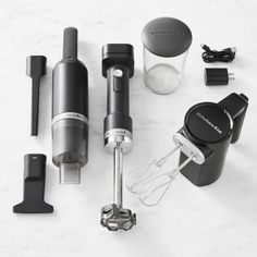 an assortment of kitchen gadgets on a white counter top with black and silver attachments