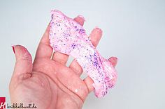 a hand holding a fake toothbrush with pink and purple flecks on it