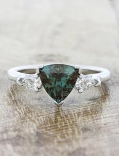 a pear shaped green diamond ring with three diamonds