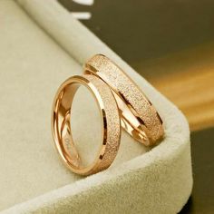 two gold rings sitting on top of a white box