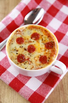 a pepperoni pizza in a white bowl on a red and white checkered tablecloth