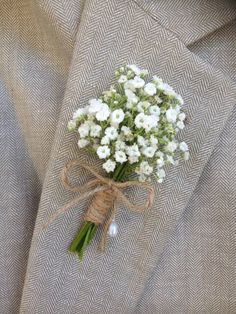 a boutonniere with baby's breath flowers tied to the lapel