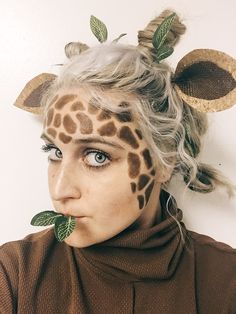 a woman with fake leaves on her head and giraffe's horns sticking out