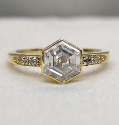 an engagement ring with a hexagon cut diamond in the center and two diamonds on each side