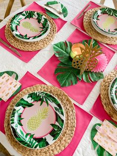 the table is set with pink and green place mats, pineapple napkins, palm leaf plates