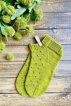 a pair of green knitted mitts sitting on top of a wooden table next to flowers