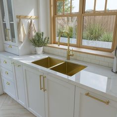 a kitchen with white cabinets and gold faucet handles on the sink countertop