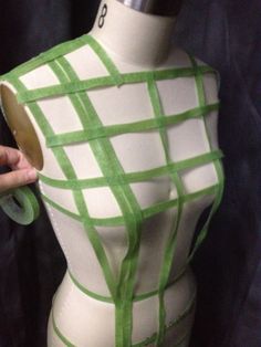 a mannequin with green tape on it's torso and hand holding the top