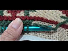 someone is crocheting the edge of a piece of fabric with a green pen