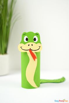 a paper tube with a snake sticking out of it's side and a plant in the background