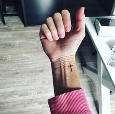 a person's arm with a cross tattoo on it, sitting in front of a computer desk