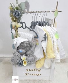 a teddy bear sitting on top of a white box filled with clothes and baby items