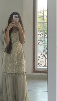 a woman taking a selfie in front of a mirror wearing a dress with sequins