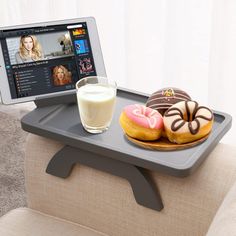 a tray with two donuts and a glass of milk on it next to a tablet