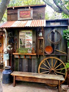 a wooden bench sitting next to a building with an old fashioned wheel on the outside