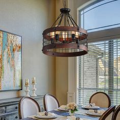 a chandelier hanging over a dining room table with place settings on the plates