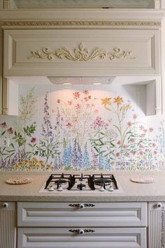 a white stove top oven sitting next to a wall with flowers painted on the side