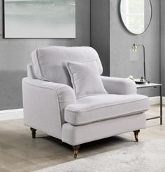 a white chair sitting in a living room next to a table with a mirror on it