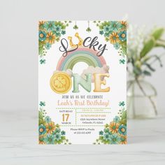 a birthday card with the number one on it and a rainbow in the middle, surrounded by flowers