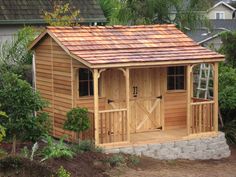 a small wooden shed with a red tiled roof and windows on the side of it