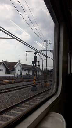 the view from inside a train window looking out at railroad tracks and houses in the distance