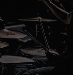 a man is playing drums in the dark