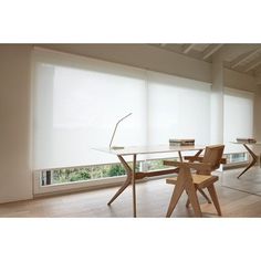 an empty room with two chairs and a table in front of large windows that have white blinds on them