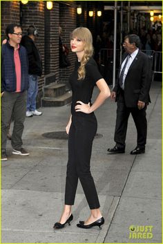 a woman in black is standing on the sidewalk