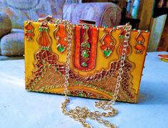 "This is a hand painted hard case acrylic hand bag with detachable gold link chain strap (with lobster clasps). It can be used as a clutch purse or shoulder bag.  Stunning palace design in bold yellow and gold colors. Large and deep enough to hold a cellphone, men's wallet and small makeup /jewelry items.  Dimensions: 7\"L x 4.33\"W x 1.97\"H. Care Instructions :  clean with a piece of cotton or a soft dry or damp cloth. Not washable. Keep away from sprays and other chemicals. SHIPPING OVERAGES WILL BE REFUNDED To explore more products please click on the below link: https://www.etsy.com/shop/Indianartoncanvas" Unique Rectangular Party Bags, Designer Square Clutch As Gift, Designer Square Clutch As A Gift, Elegant Hand Painted Rectangular Bag, Elegant Hand Painted Rectangular Bags, Elegant Orange Clutch For Party, Orange Rectangular Clutch For Formal Occasions, Gold Rectangular Clutch For Festivals, Elegant Orange Clutch As A Gift