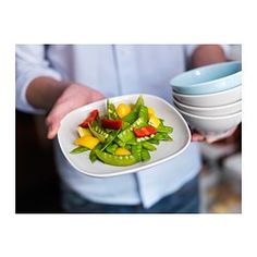 a person holding a plate with vegetables on it