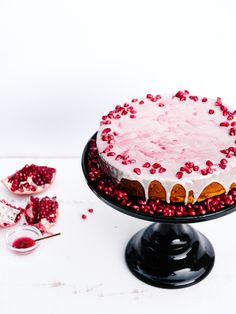 a cake with white frosting and pomegranate toppings on a plate