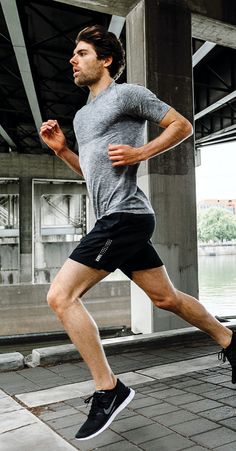 a man is running on the sidewalk in front of a bridge and water underpass