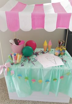 an ice cream stand with pink and white striped awnings, balloons, confetti, and other items on it