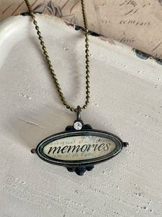 "Ronnie would never let go of her memories   The necklace features a mini shadow box pendant that encases the word \"Memories.\" The pendant has a vintage appearance and includes a small rhinestone for added detail and sparkle. The necklace itself is designed with a ball chain and measures 18\" in length. It is commonly worn closer to the neckline due to its shorter length. The necklace is secured with a lobster clasp, which is a popular type of closure in jewelry. This necklace offers a sentime Vintage Personalized Charm Necklace For Keepsake, Vintage Personalized Charm Necklaces As Gift, Personalized Vintage Charm Necklaces As Gift, Personalized Vintage Charm Necklaces For Gift, Vintage Engraved Charm Necklaces As Keepsakes, Vintage Engraved Charm Necklaces For Keepsake, Vintage Personalized Pendant Charm Necklaces, Vintage Oval Pendant Charm Necklace As Gift, Vintage Oval Pendant Charm Necklace For Gift