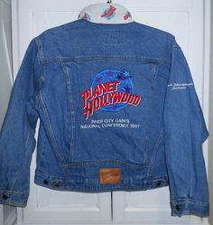 a denim jacket with the logo of planet hollywood hanging on a white door in front of a doorway