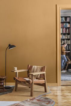 a living room with a chair, table and bookshelf in the middle of it