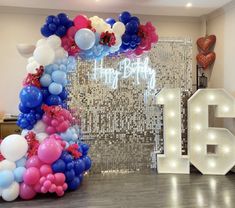 balloons and streamers decorate the entrance to a 16th birthday party in front of an illuminated backdrop