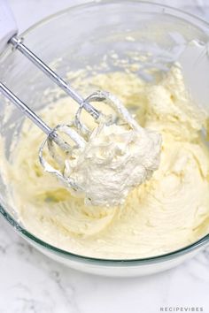 a mixing bowl filled with whipped cream and a whisk in the middle, on a marble countertop