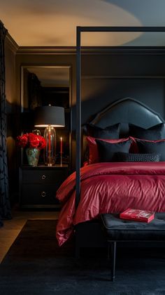 a bed with red sheets and pillows in a dark room next to a black dresser