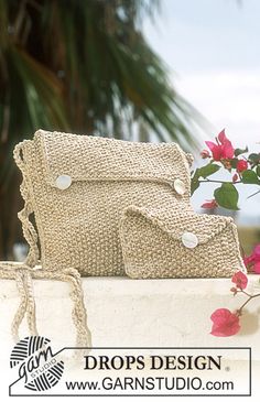 a white purse sitting on top of a table next to a pink flower and palm tree