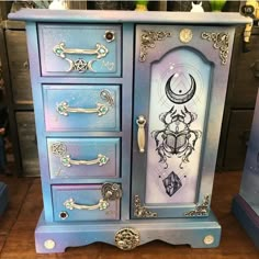 a blue and purple cabinet with an ornate design on the door, drawers and handles