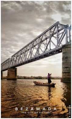 two people in a small boat on the water under an overpass with a sky background