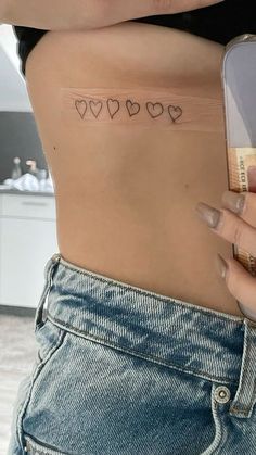 a woman's stomach with small hearts tattooed on the lower part of her belly