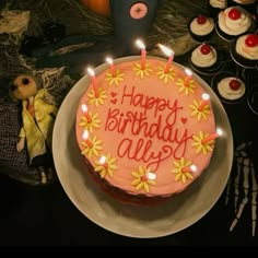 a birthday cake with candles on it sitting next to cupcakes