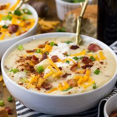 two white bowls filled with potato soup and topped with bacon, cheese and green onions