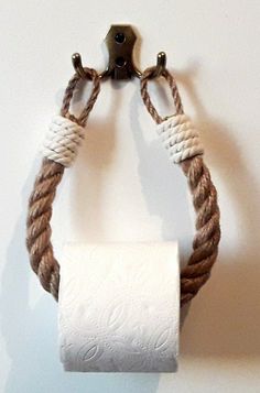 a roped up toilet paper holder hanging on a wall